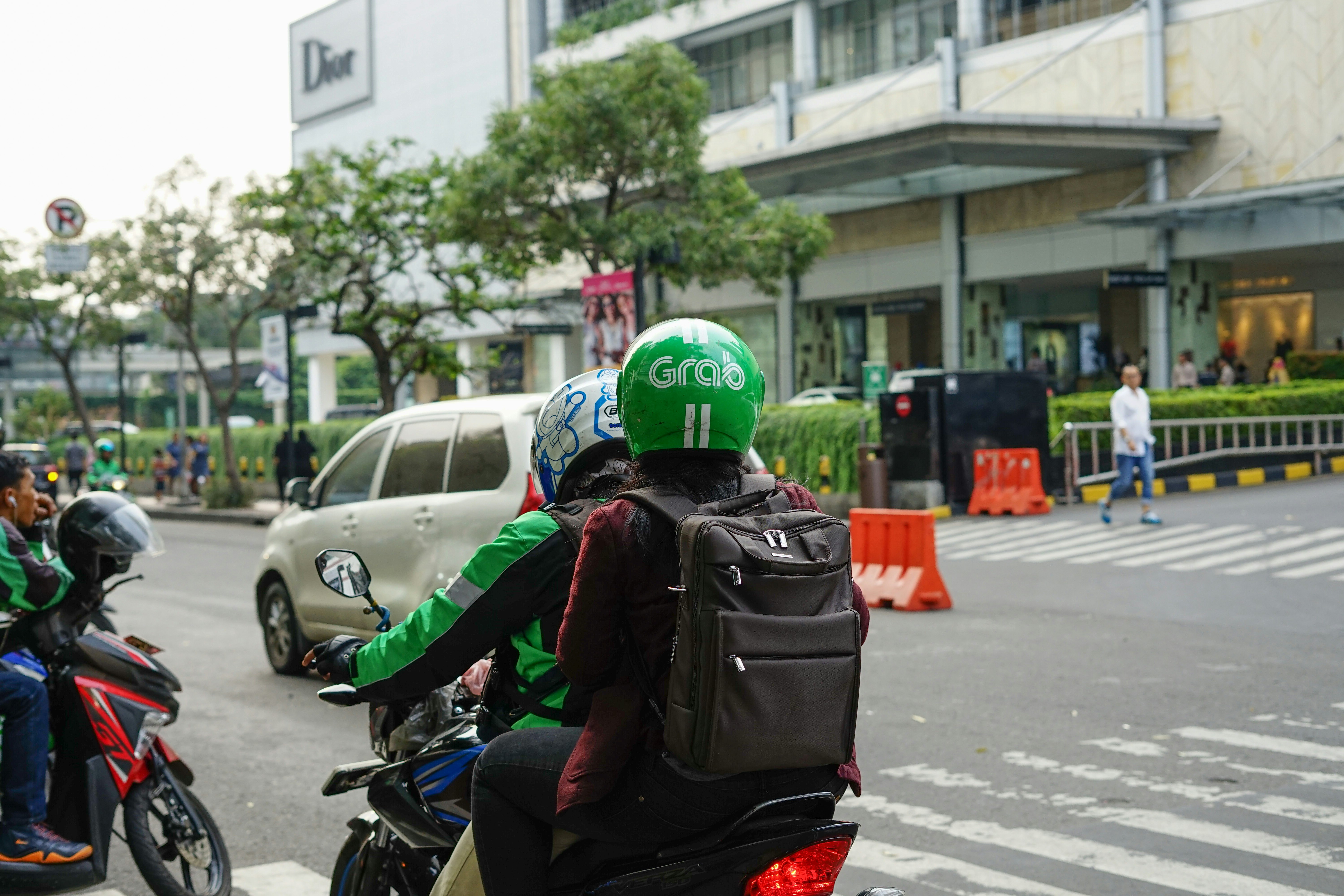 Grab Bike Driver picking up passenger. Grab is a technology company that offers wide range of ride-hailing and logistics services through its app in Southeast
