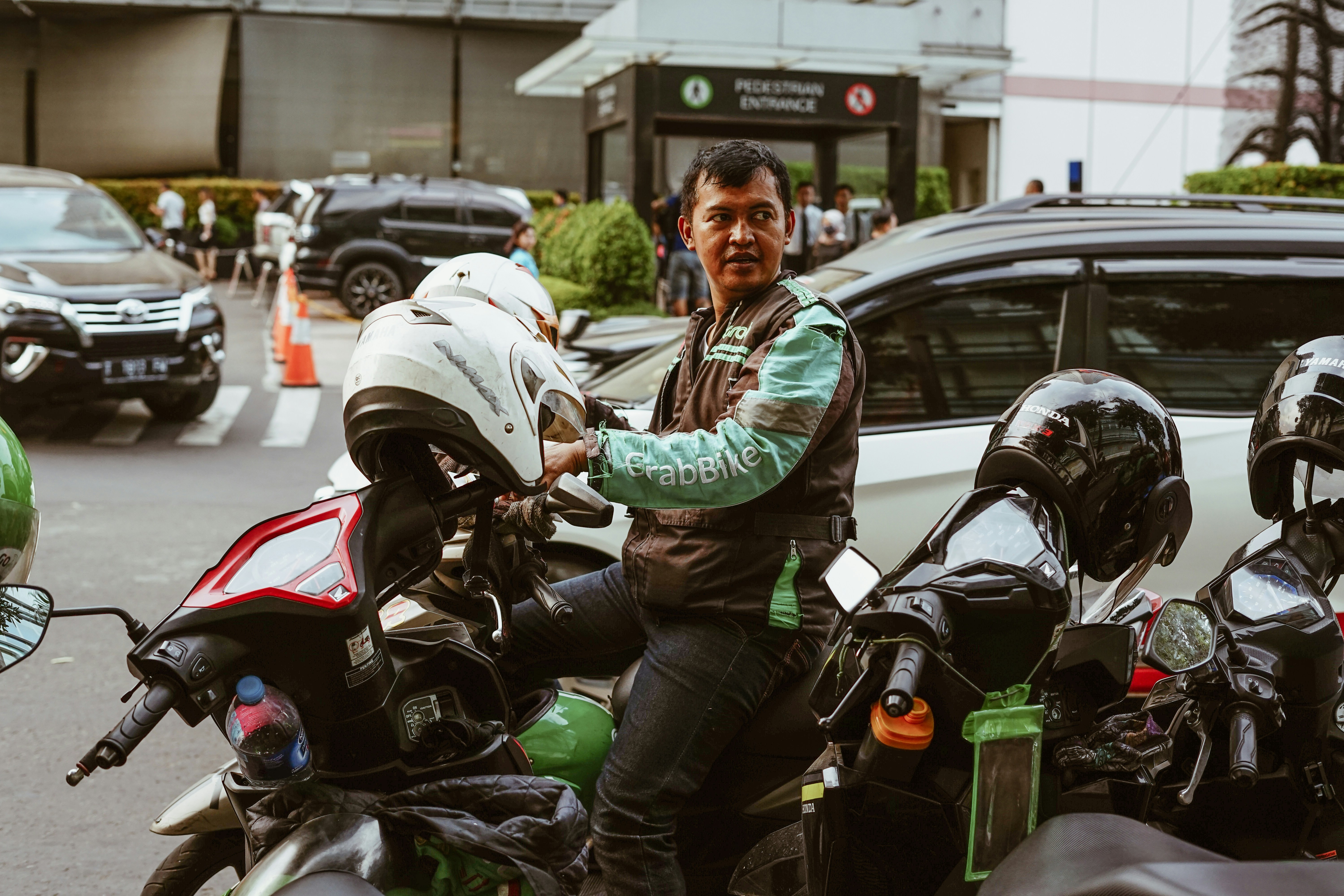 Grab Bike Driver picking up passenger. Grab is a technology company that offers wide range of ride-hailing and logistics services through its app in Southeast