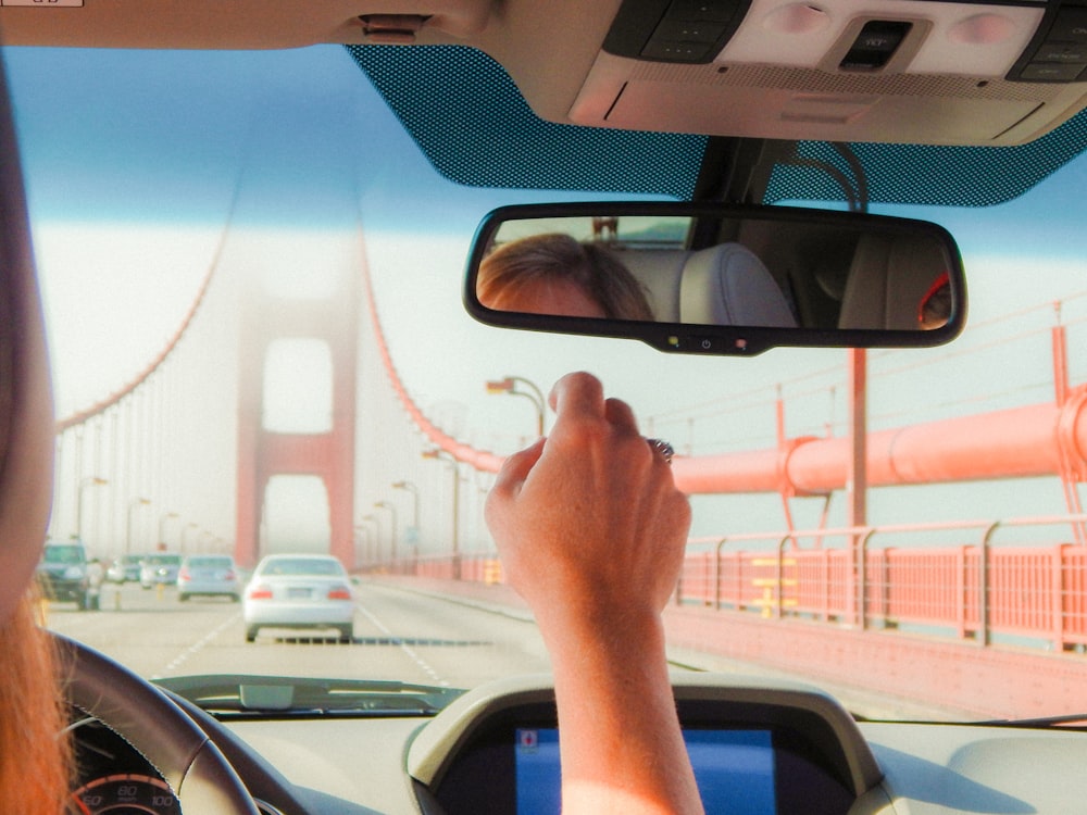 a woman driving a car over a bridge