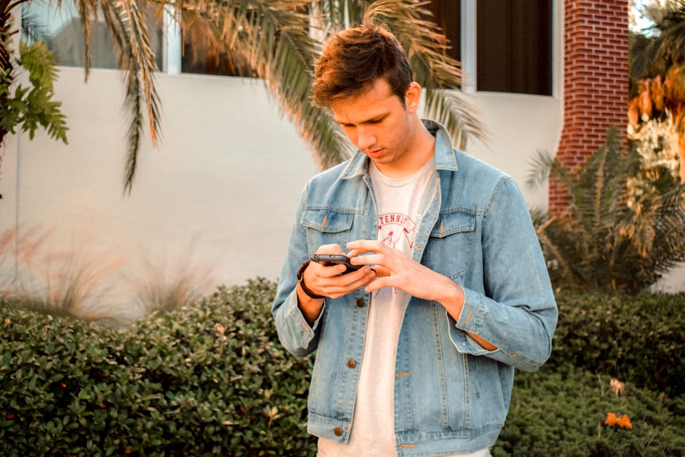 man in blue denim jacket using phone