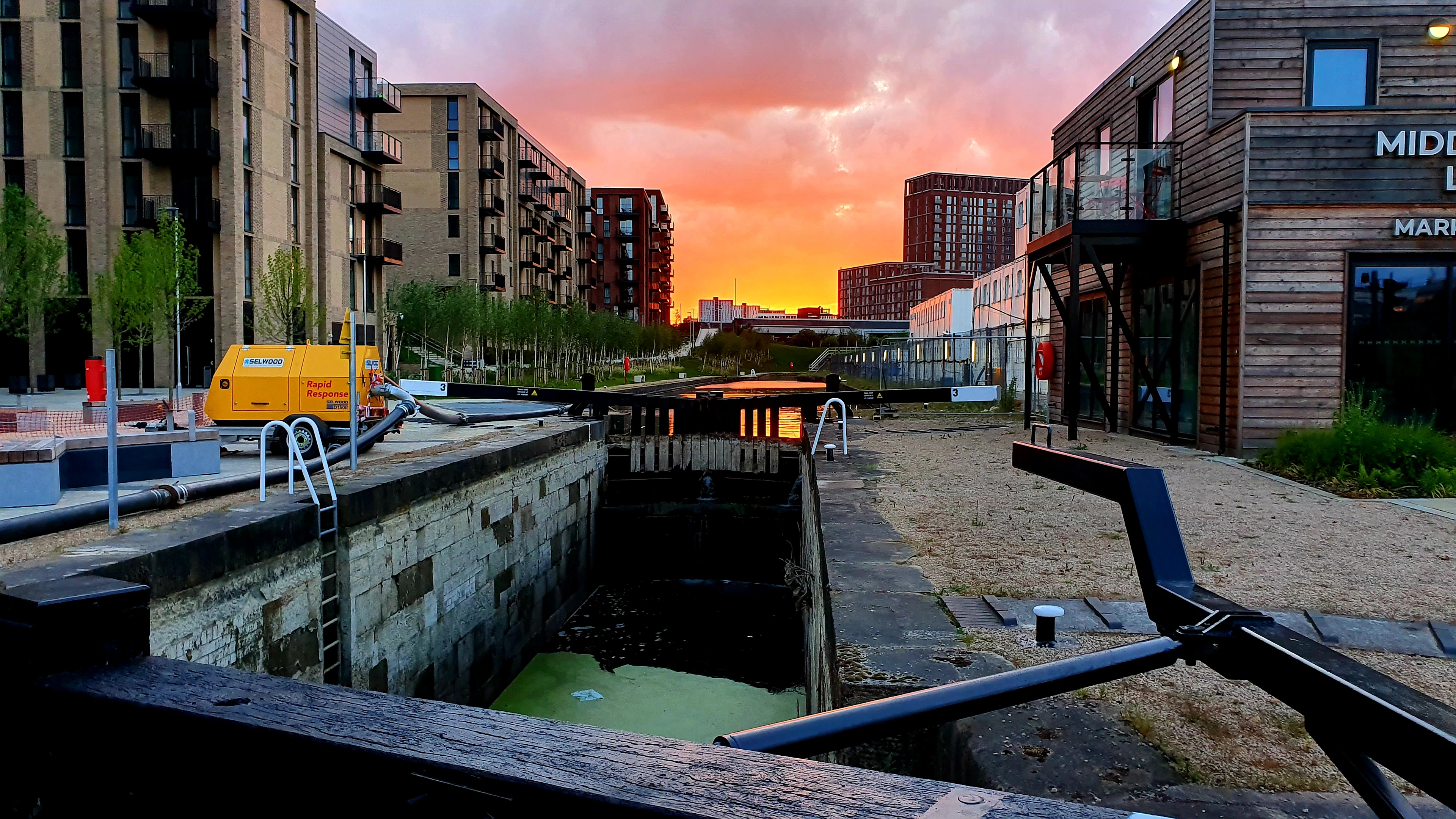 A canal lock in Manchester at sunset, warehouses and new flats along the water