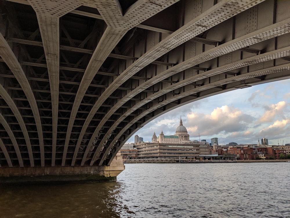 grey concrete buildings near body of water through bridge