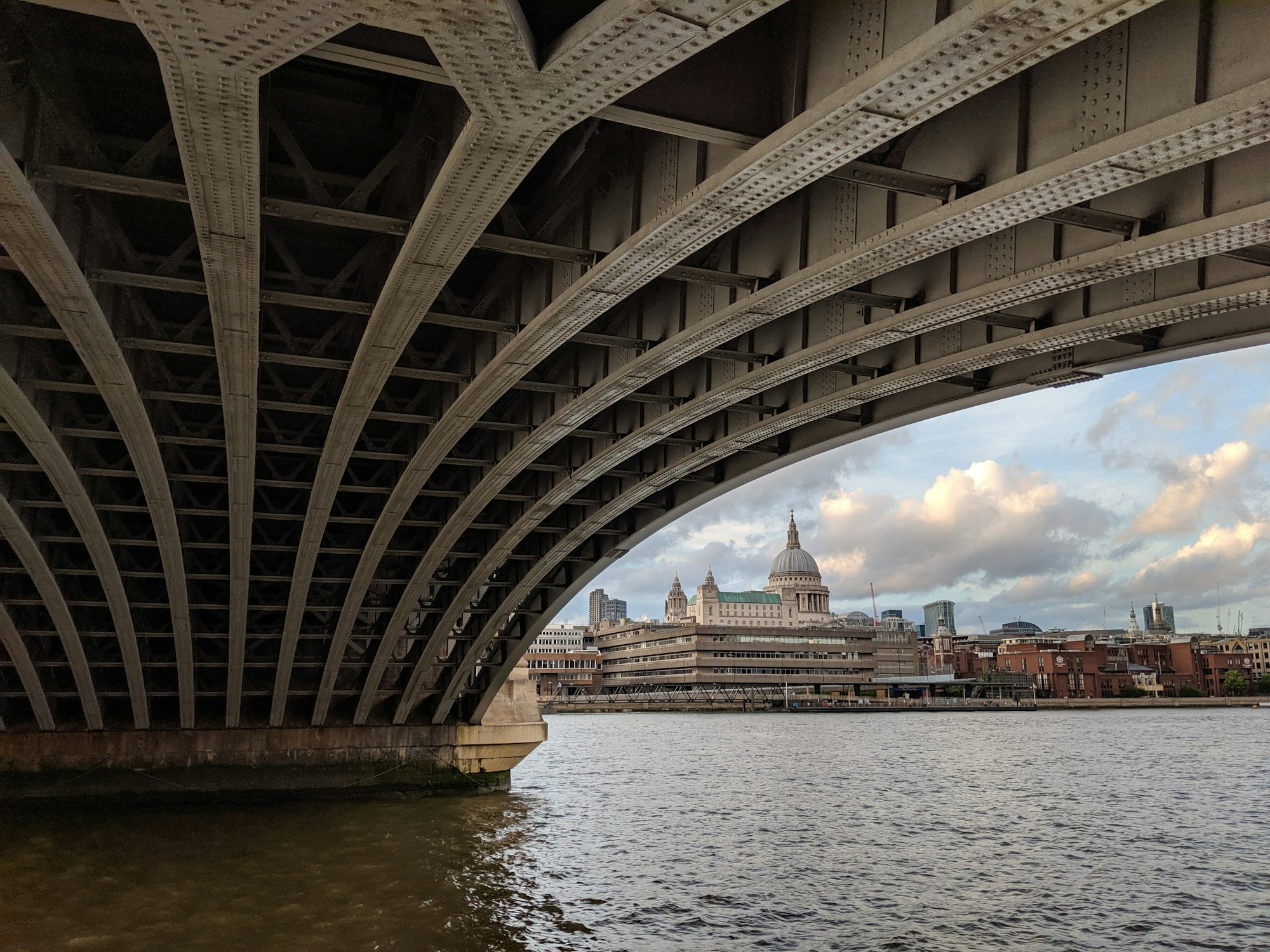 grey concrete buildings near body of water through bridge