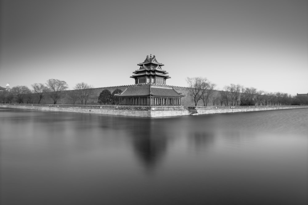 grayscale photo of temple near body of water