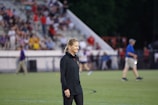 A fashionable woman wearing a warm coat at a sports field.