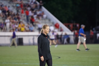 A stylish woman bundled warmly on the sidelines at a sports game.