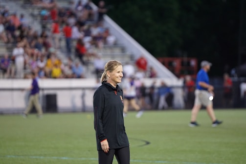 A fashionable woman wearing a warm coat at a sports field.