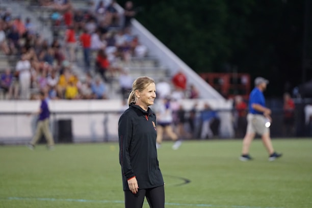 A stylish woman bundled warmly on the sidelines at a sports game.