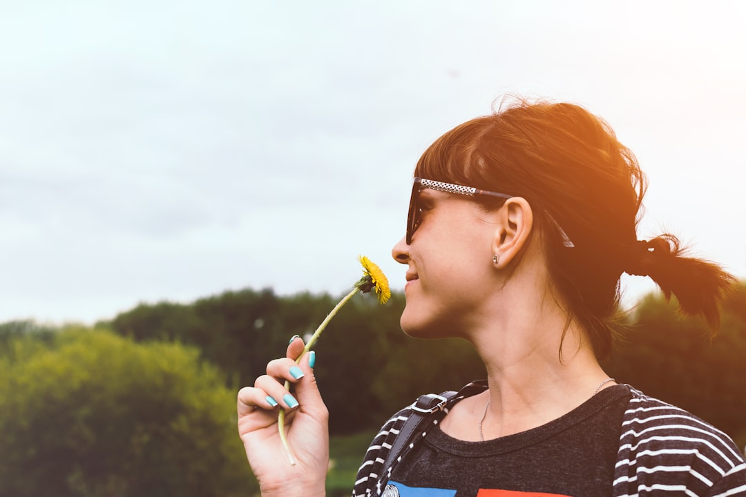 woman in sunglasses smelling yellow flower