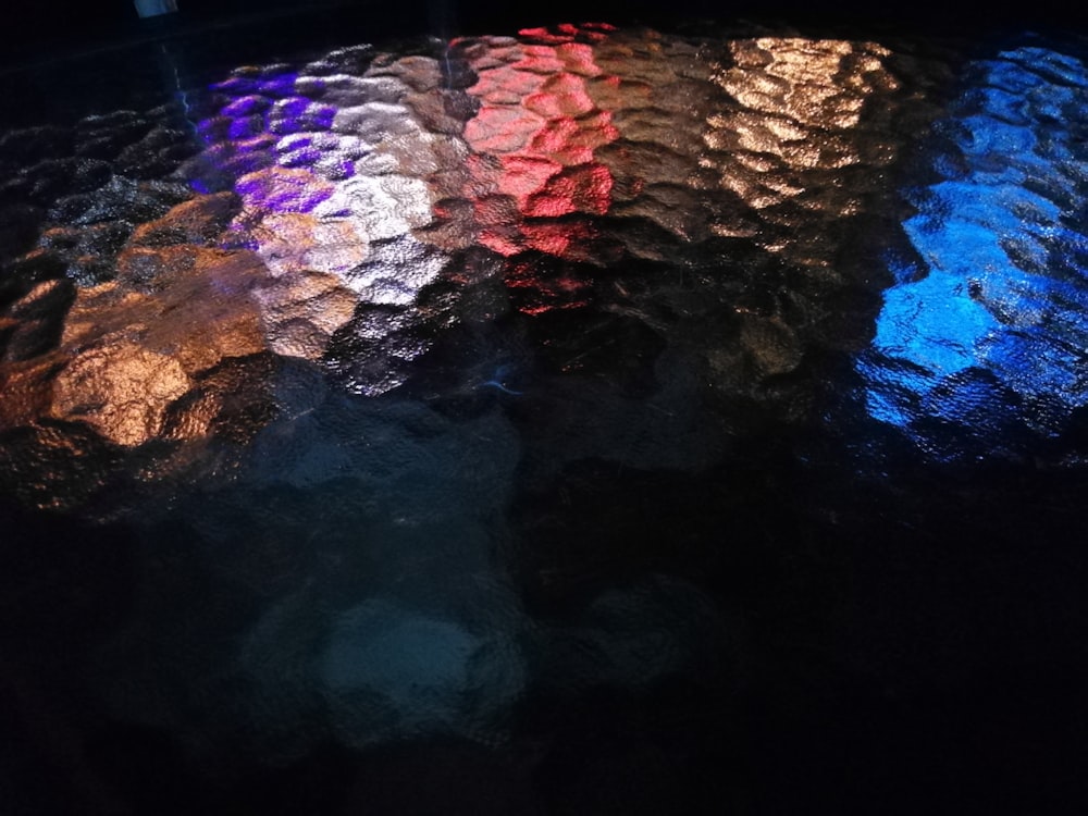 um close up de uma luz colorida refletindo de uma superfície preta