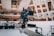 A professional video camera is mounted on a mechanical arm within a modern architectural setting. The background features sleek, curved structures with visible balconies and people observing the scene.