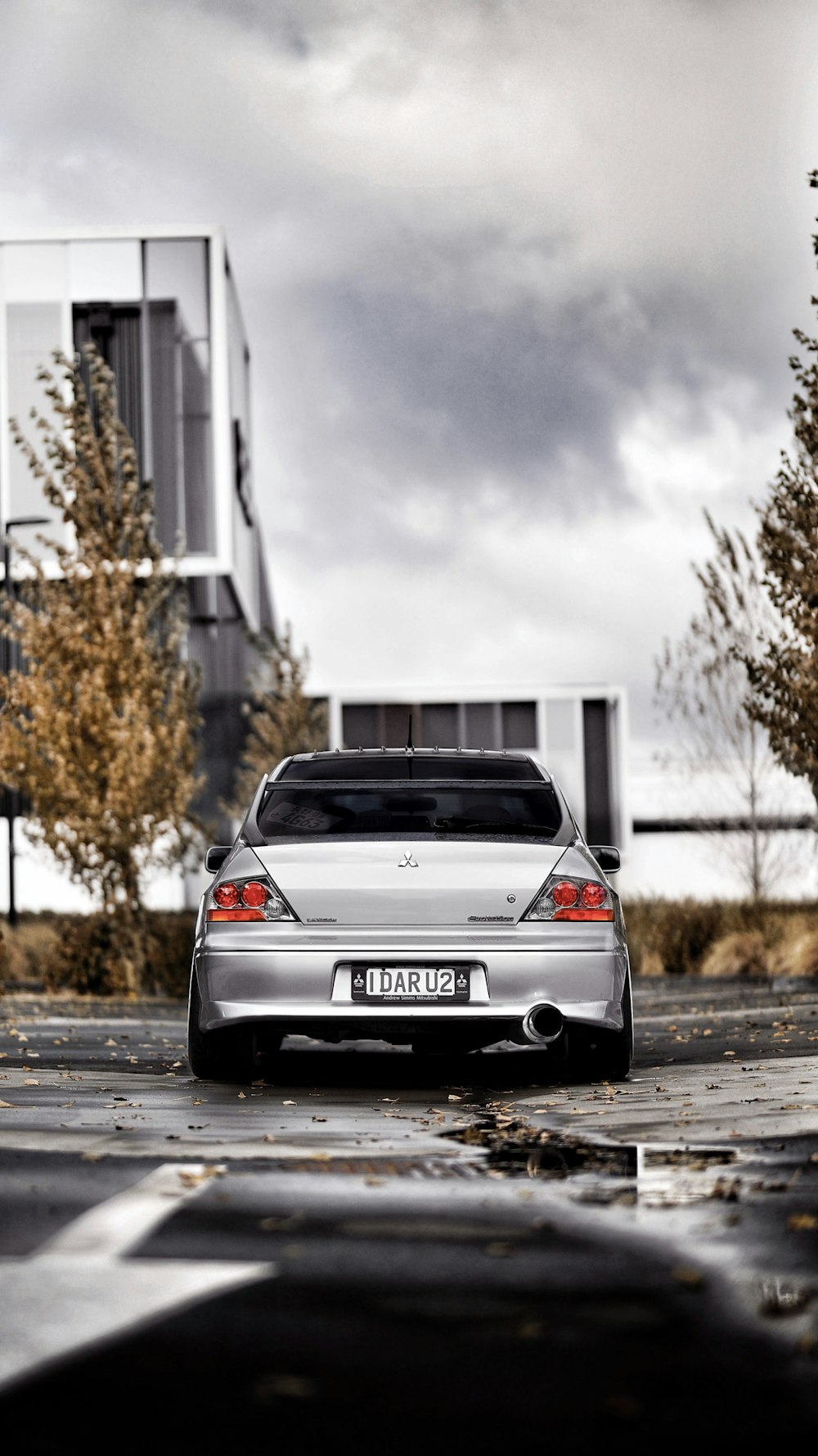 silver car parking near concrete building under gray skies