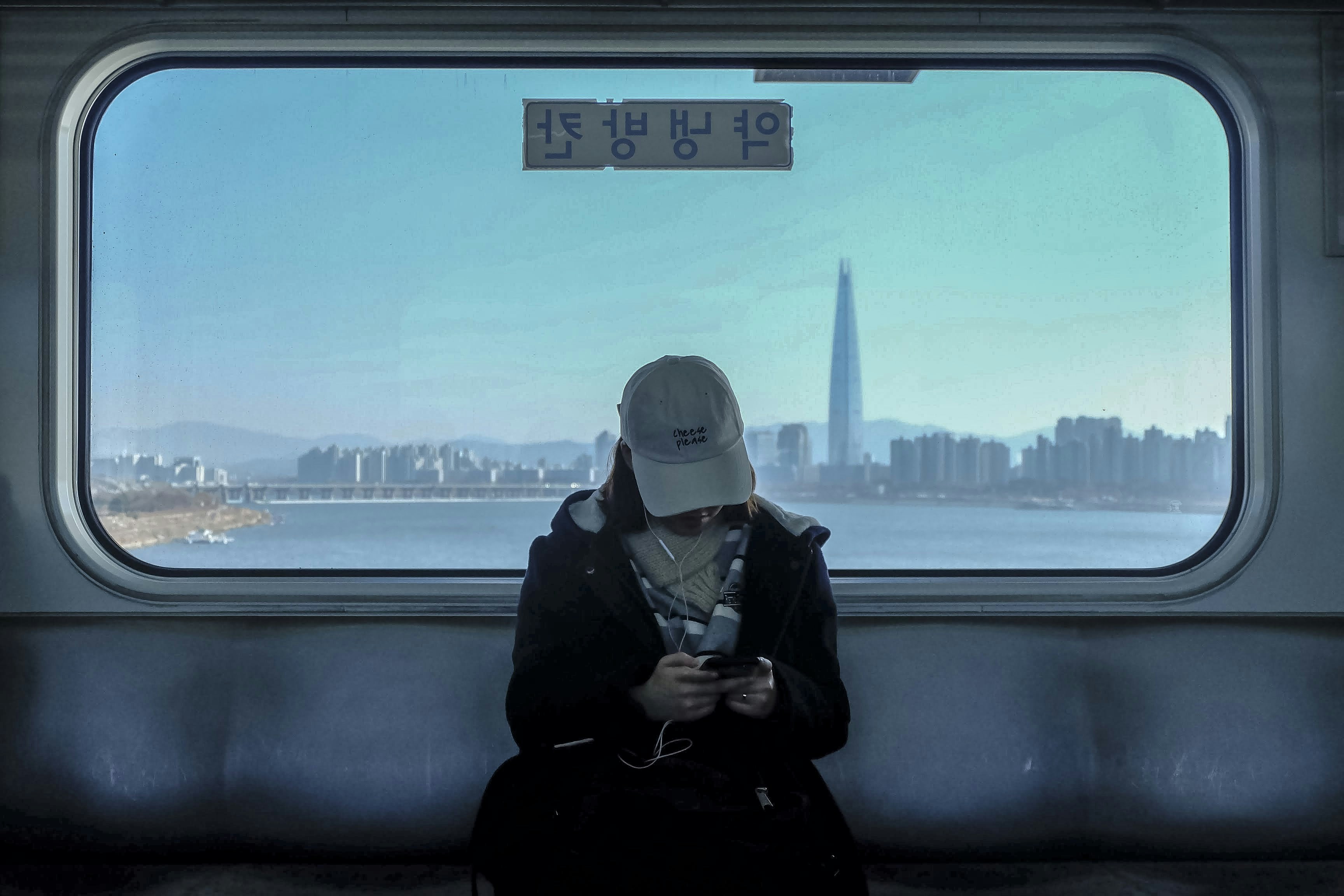 woman wearing coat and earbuds, Girl in the train. Overlooking Gangnam.