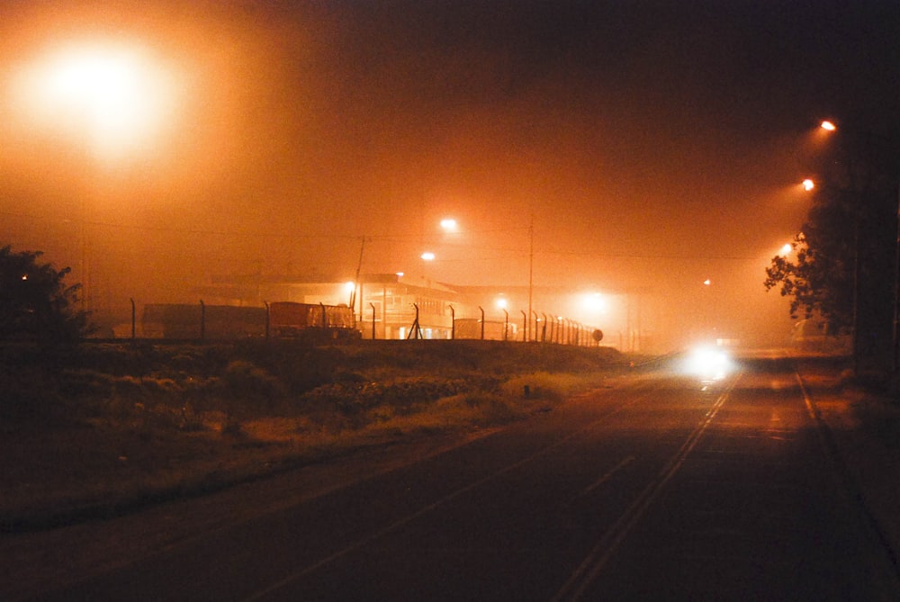 a foggy street with street lights and a train on the tracks