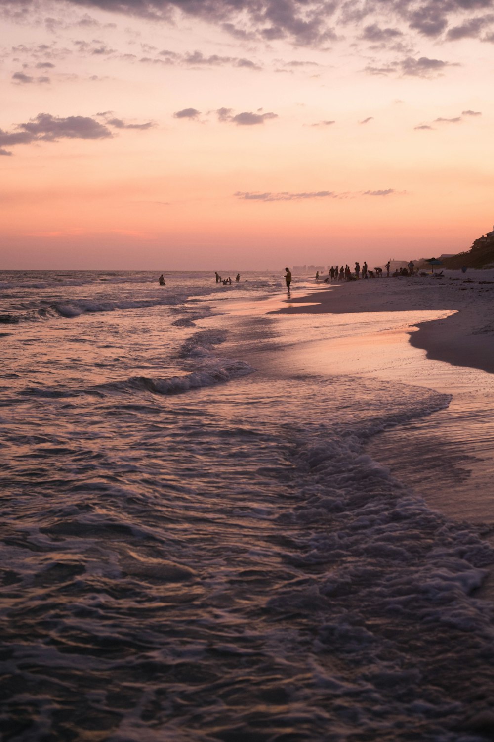 people near seashore viewing sea under orange and gray skies