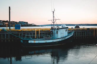 A technician testing electrical connections on a small private boat docked at sunset.