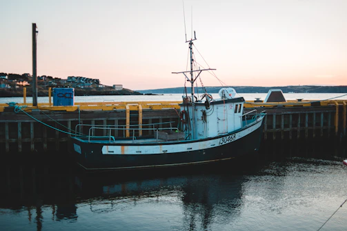 A technician testing electrical connections on a small private boat docked at sunset.