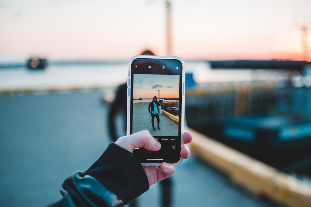 person taking picture of woman standing on pavement