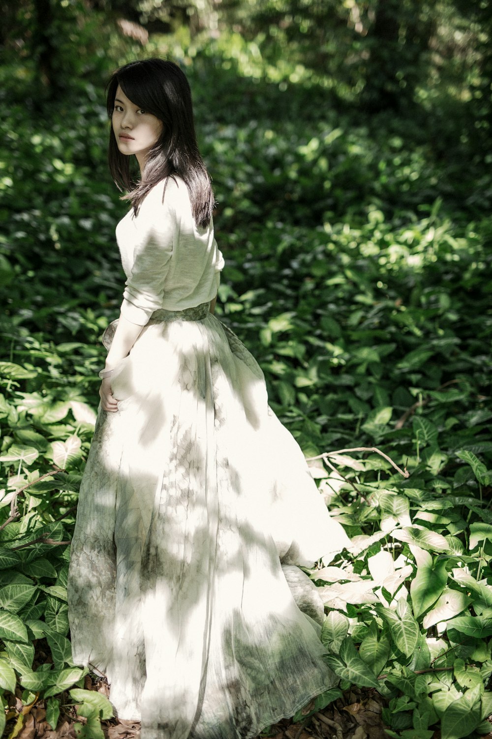 Frau im weißen langärmeligen Kleid, umgeben von Pflanzen