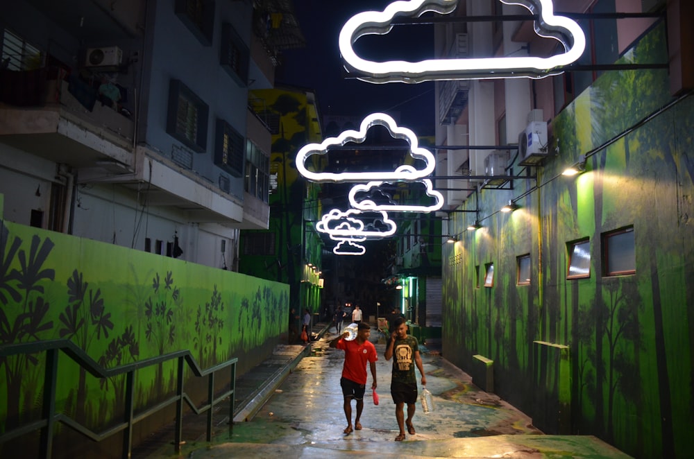 two men walking between green walls