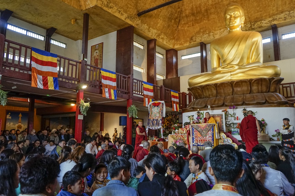 people gathering near golden Buddha statue