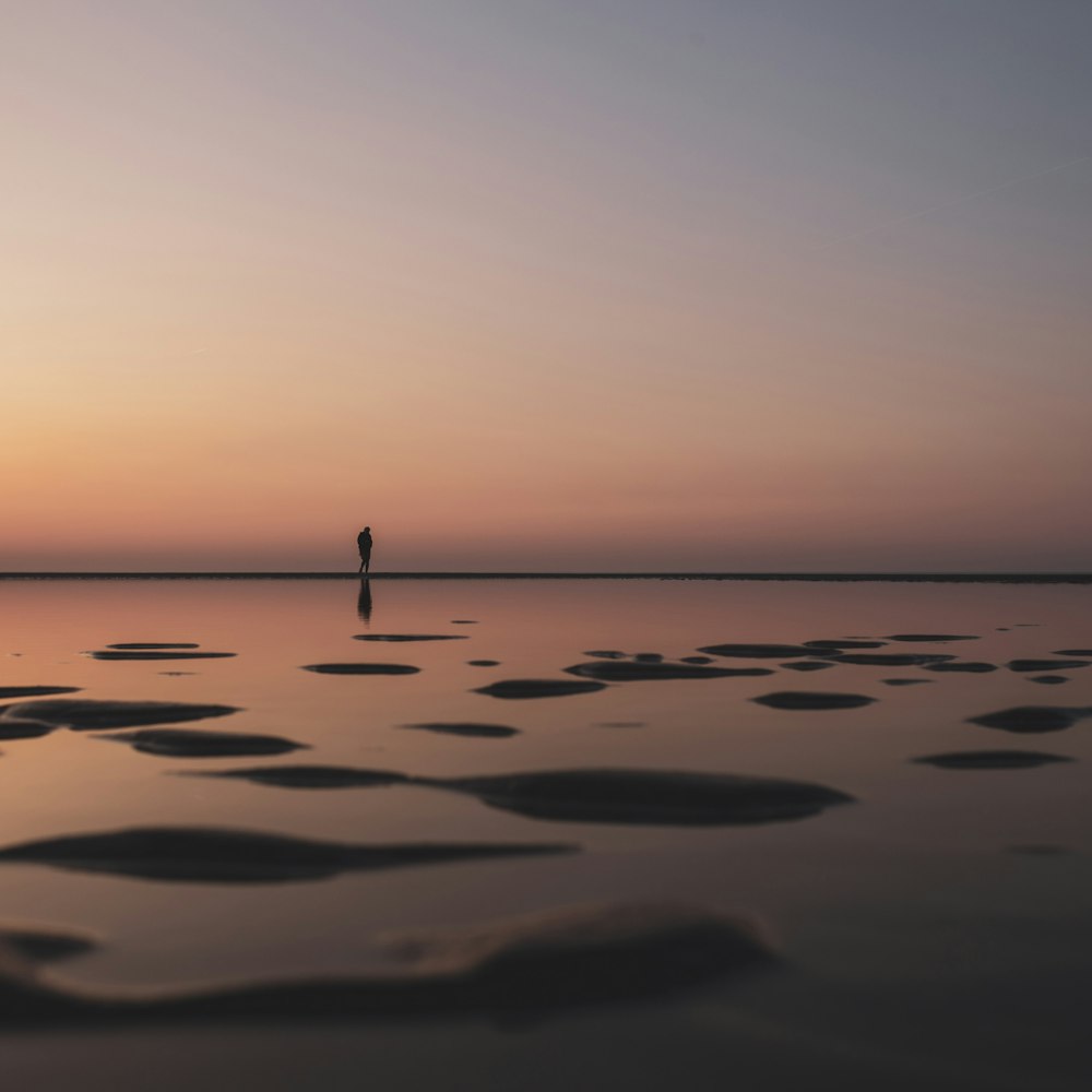silhouette of person standing on body of water