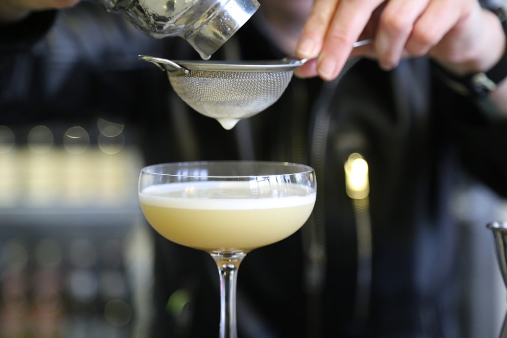 person pouring liquid on margarita glass