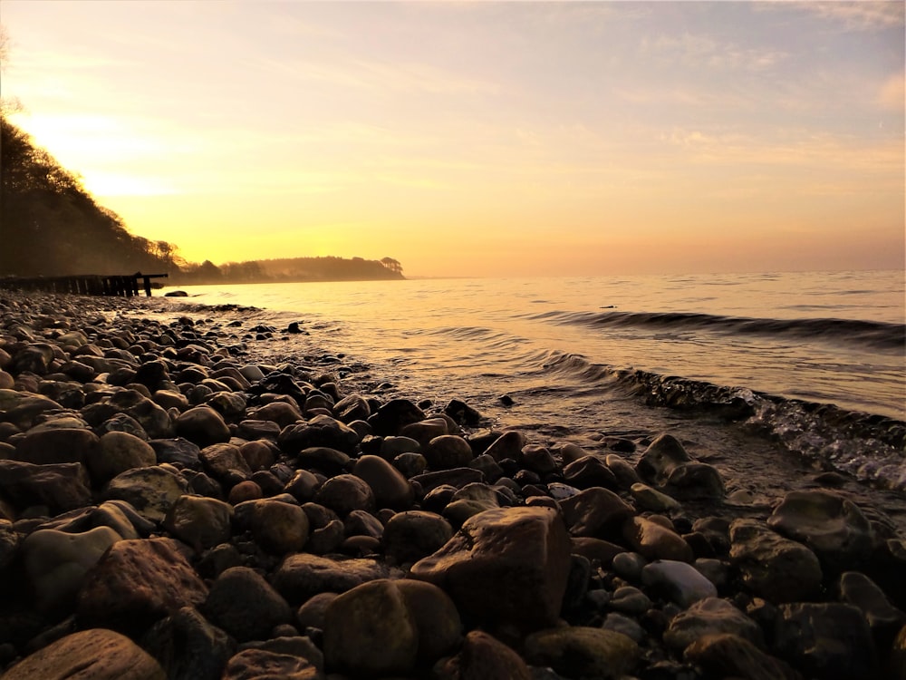 rock formations near seashore viewing calm sea under yellow skies