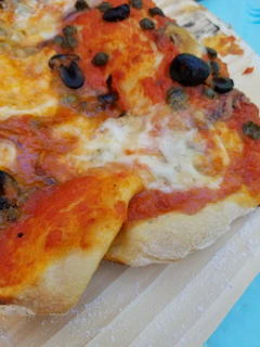 Close-up of a freshly baked pizza with melted cheese and colorful toppings on a wooden board