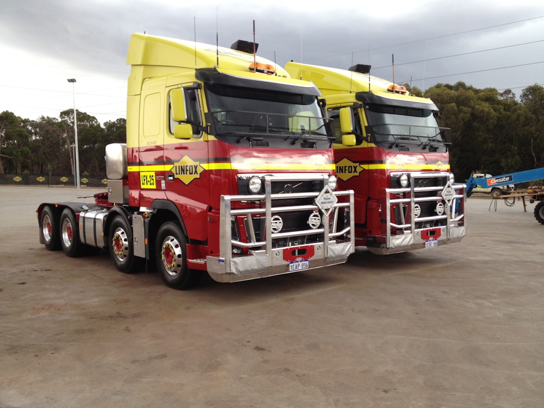 two red-and-green semi trucks parked at road