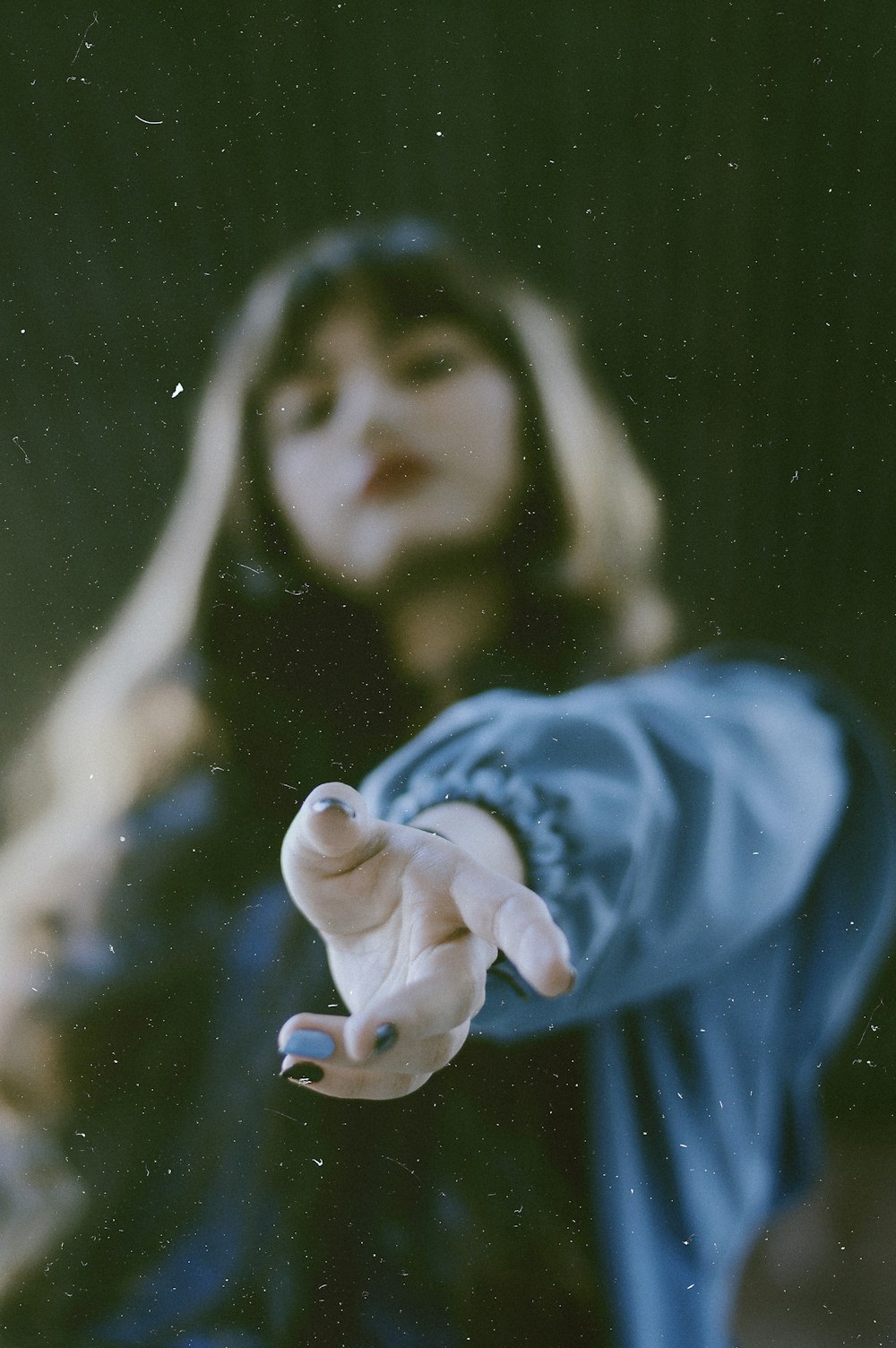 woman in blue jacket reaching out using left hand