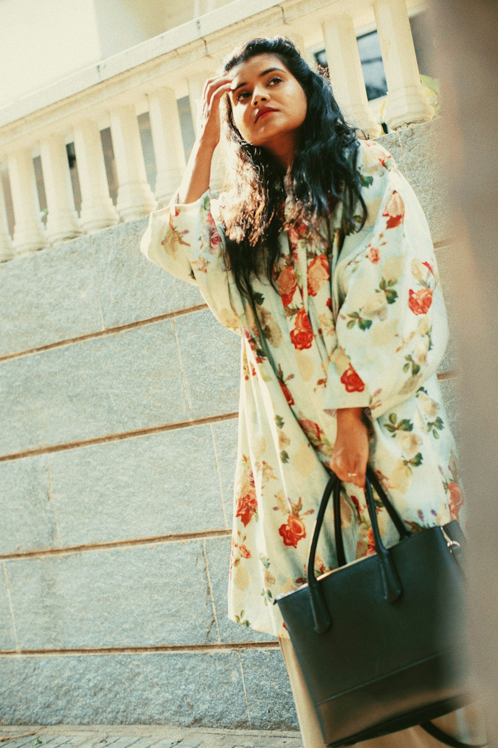 woman carrying tote bag standing in front of brick wall