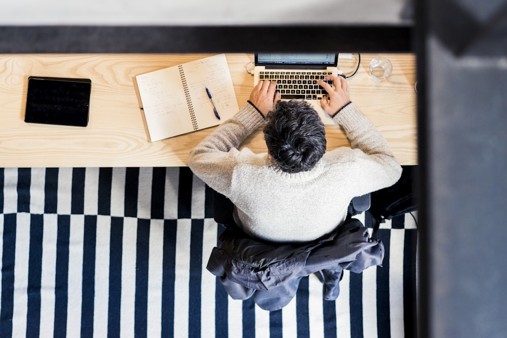 man sitting by the desk using laptop computer