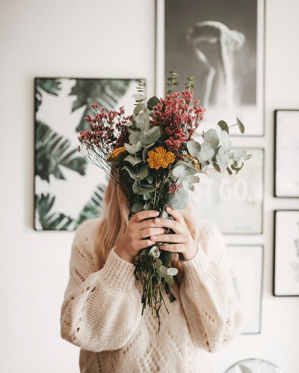 mujer que esconde su rostro con ramo de flores