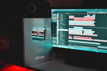 A YouTube Silver Play Button award is placed next to a computer monitor displaying music production software with various audio tracks and timelines.