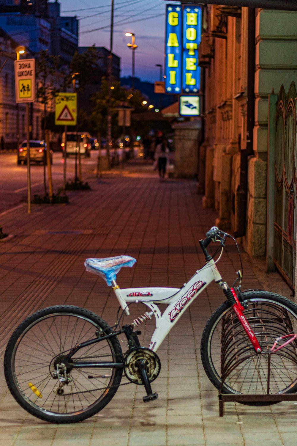 茶色の自転車ラックに駐車された白と黒のフルサスペンション自転車