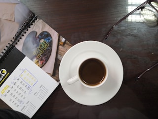 A calendar marked with monthly payment dates beside a laptop and coffee.