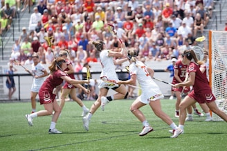 A dynamic action shot of the women's lacrosse team during a game.