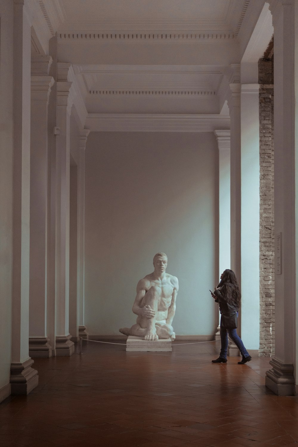 woman walking in front of man's sculpture