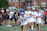 A young athlete celebrating a victory on the field with teammates cheering around.