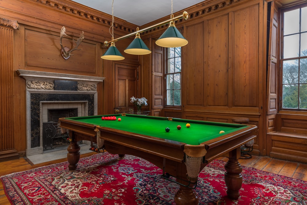brown and green billiard table near fireplace