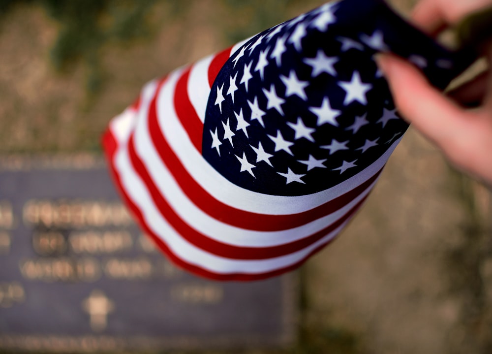 a person holding a cell phone in front of a flag