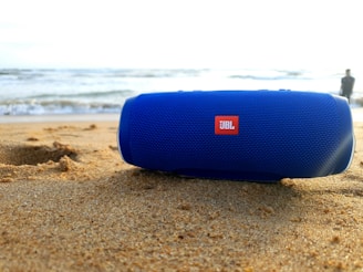 A group of friends enjoying music from a Bluetooth speaker at a beach.