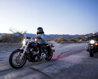 Motorcyclists riding together on a scenic road at sunset with blue and black tones.
