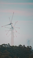 Wind turbine blades turning gently against a bright sky in an industrial setting.