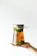 A hand holding a large glass jar filled with a liquid and sliced green fruits. The jar is topped with a metal lid and covered with plastic wrap.