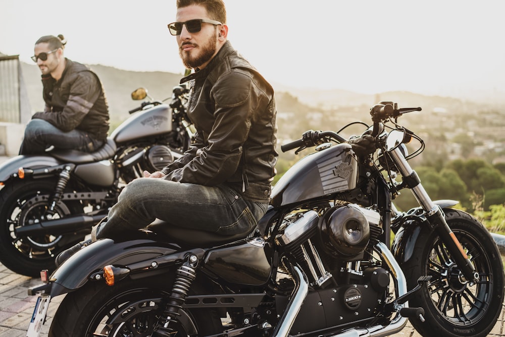 two men sitting on two parked cruiser motorcycles