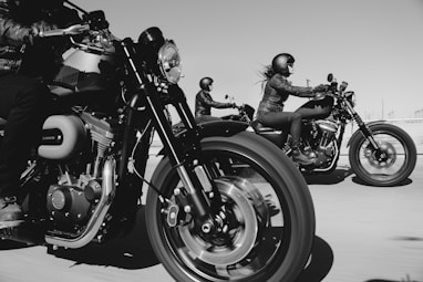 black and white photo of people riding motorcycle