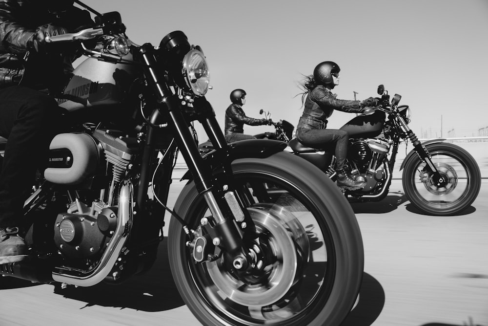 black and white photo of people riding motorcycle