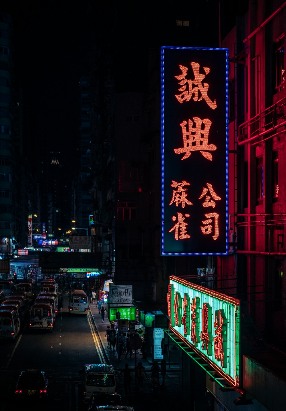 lighted neon sign in busy city street at night